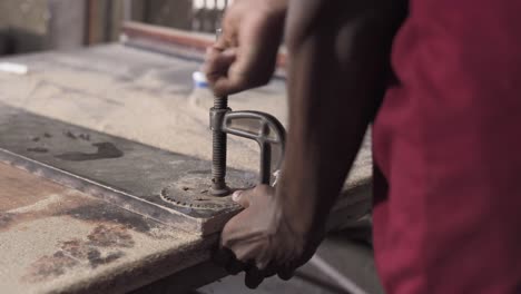 strong black man screwing an iron plate to a table for craft work application