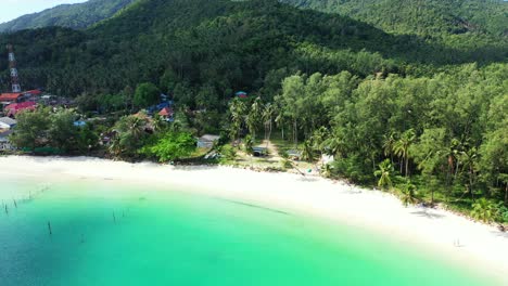 Paradiesischer-Exotischer-Strand-Mit-Weißem-Sand,-Umspült-Von-Türkisfarbener-Lagune,-Gesäumt-Von-Tropischen-Bäumen-In-Der-Nähe-Von-Ferienresorts-In-Thailand