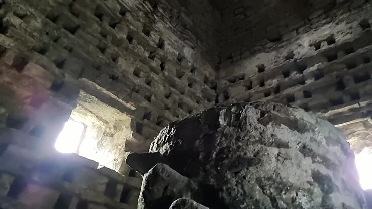 Inside old stone Penmon priory dovecot with stone wall nesting box and window light