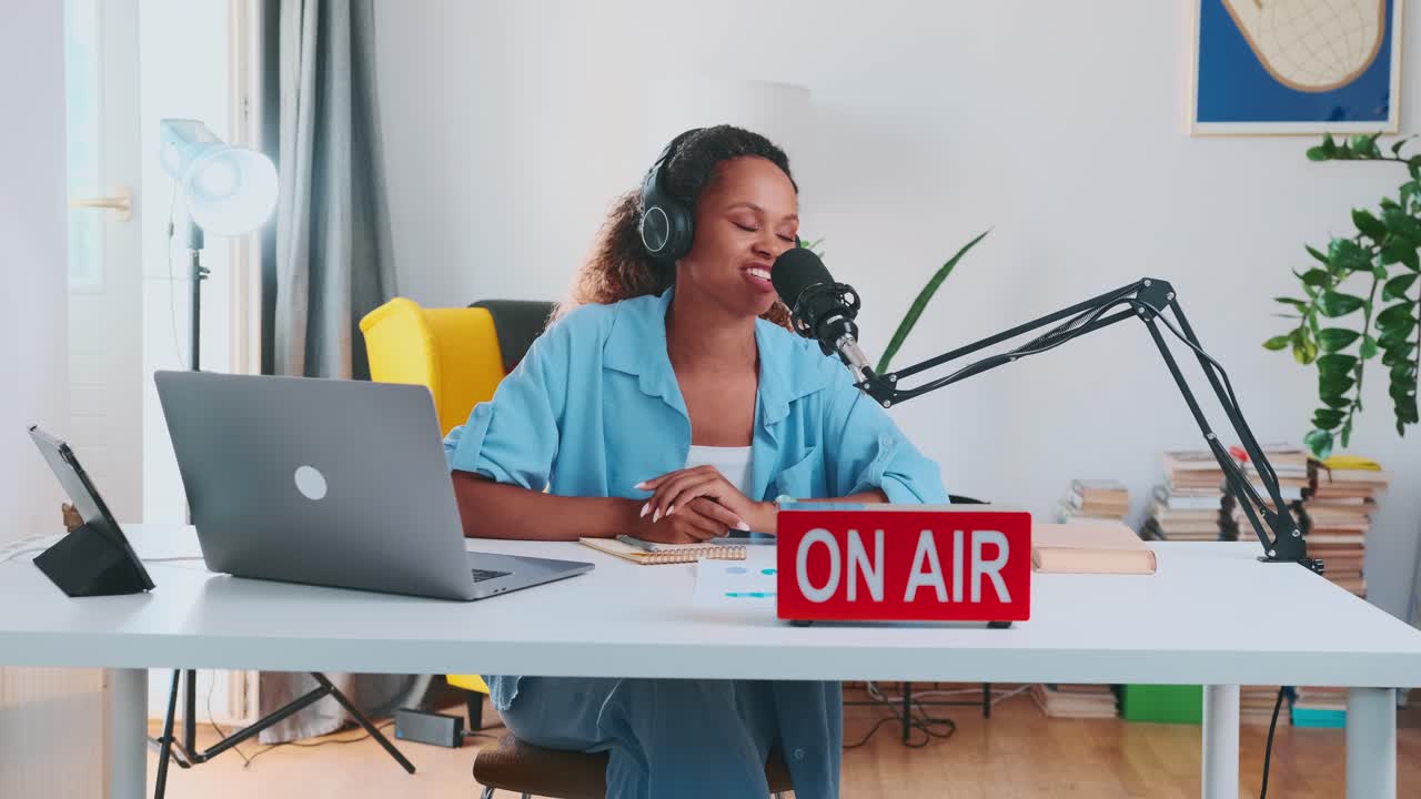 Young african american woman puts on headphones and speaks into microphone
