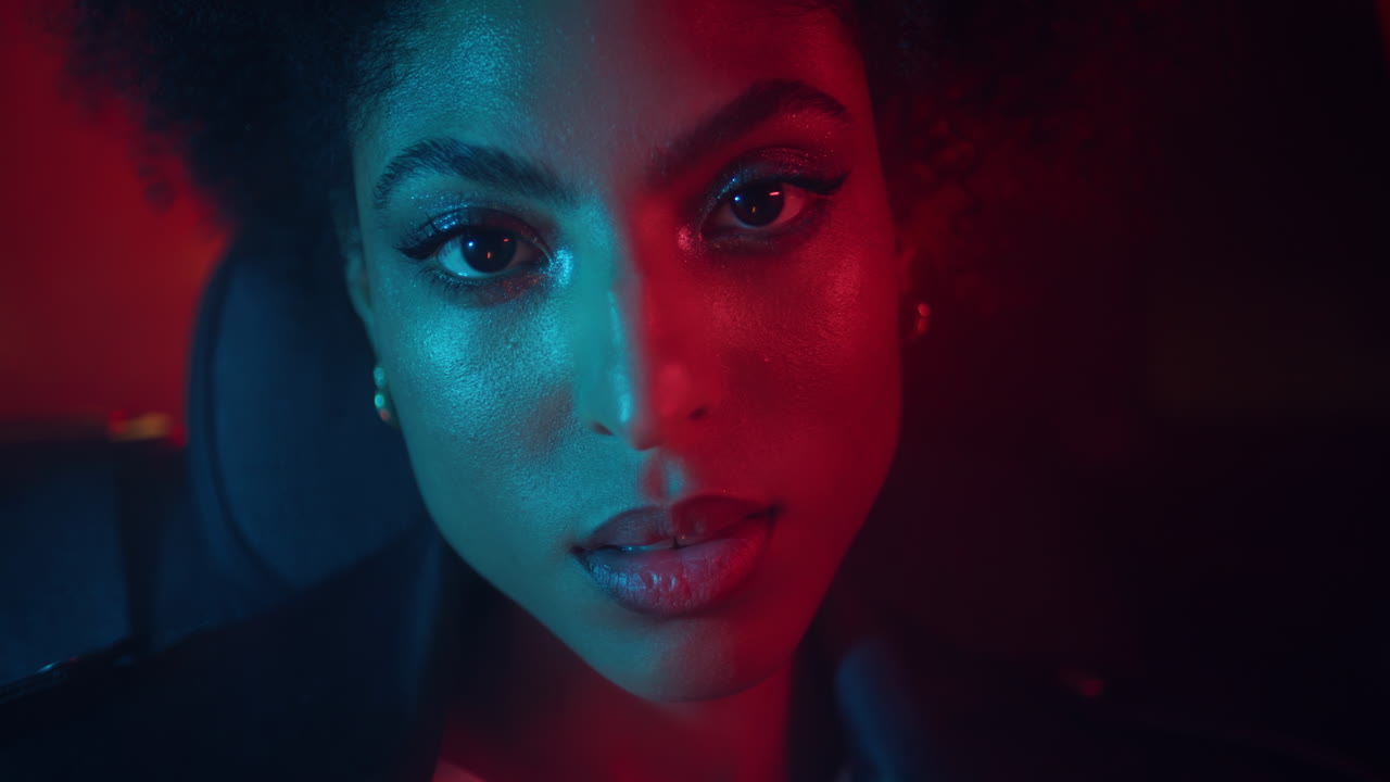 Primo piano del viso di una donna con trucco appariscente illuminato da luce rossa al neon. signora