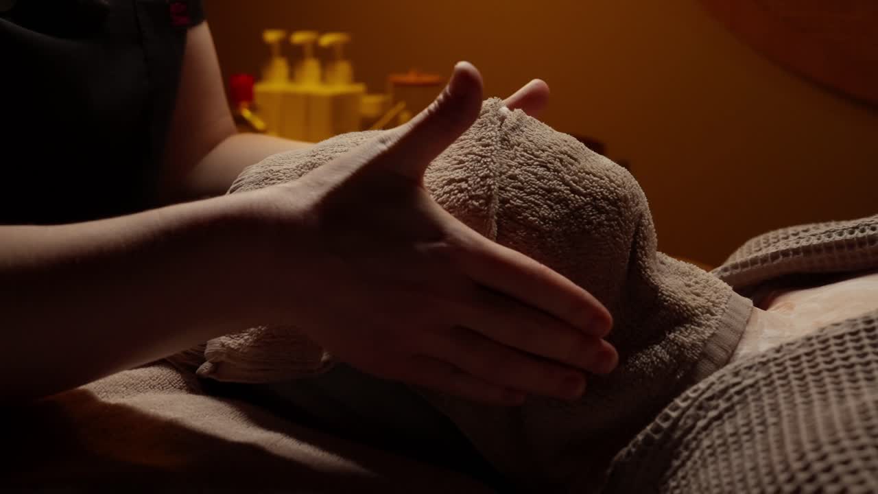 Terapista della spa che applica un asciugamano caldo sul viso del cliente durante il trattamento