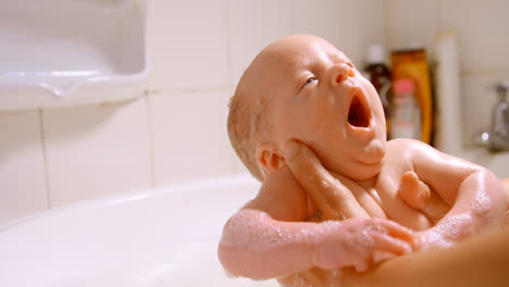 mother giving her baby boy a bath in bathroom at home 4k