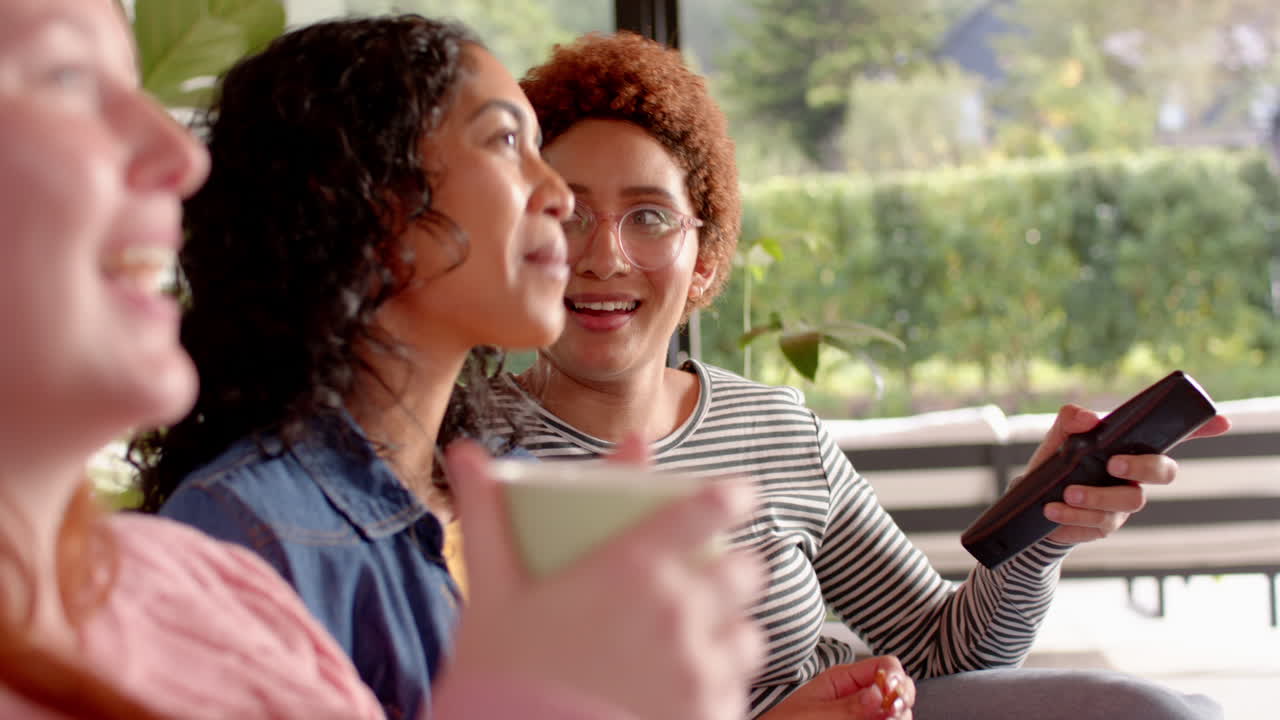 Laughing and enjoying time, diverse female friends hanging out together indoors
