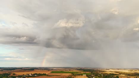 time lapse the rainbow over the green field after storm with rain, during outumn, aerial view under heavy clouds before thunderstorm