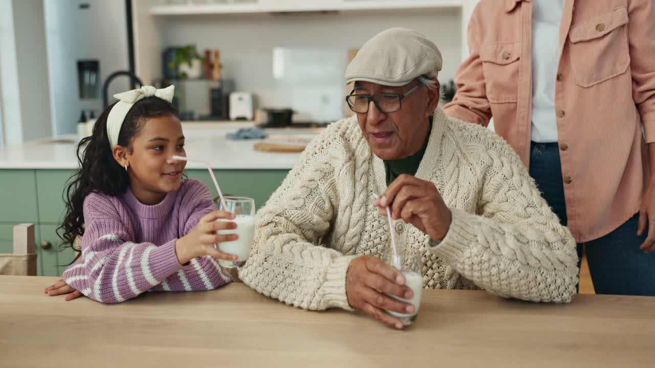 Grandfather, daughter, and granddaughter drinking milk together at the kitchen table
