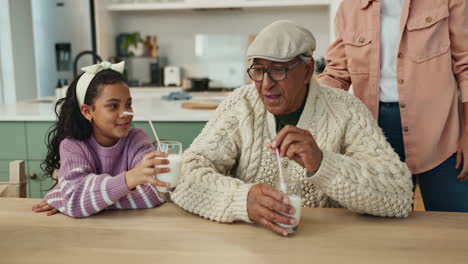 grandfather, daughter, and granddaughter drinking milk together at the kitchen table