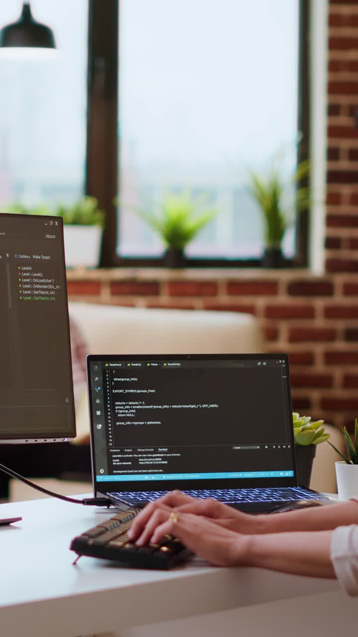 Vertical Video IT specialist types code on dual monitors in a cozy home office