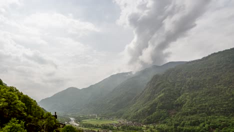 this still timelapse (with pan zoom) captures a sweeping view of a lush valley around locarno, switzerland. rolling green mountains frame a winding river below, while a storm cloud tower builds.