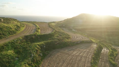 AERIAL:-Sun-Halo-and-Rays-Shining-in-Camera-While-Drone-Flies-Above-Green-Malta-Coastline