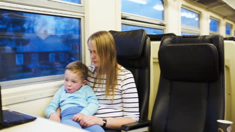 mother and her son watching movie on laptop in the train