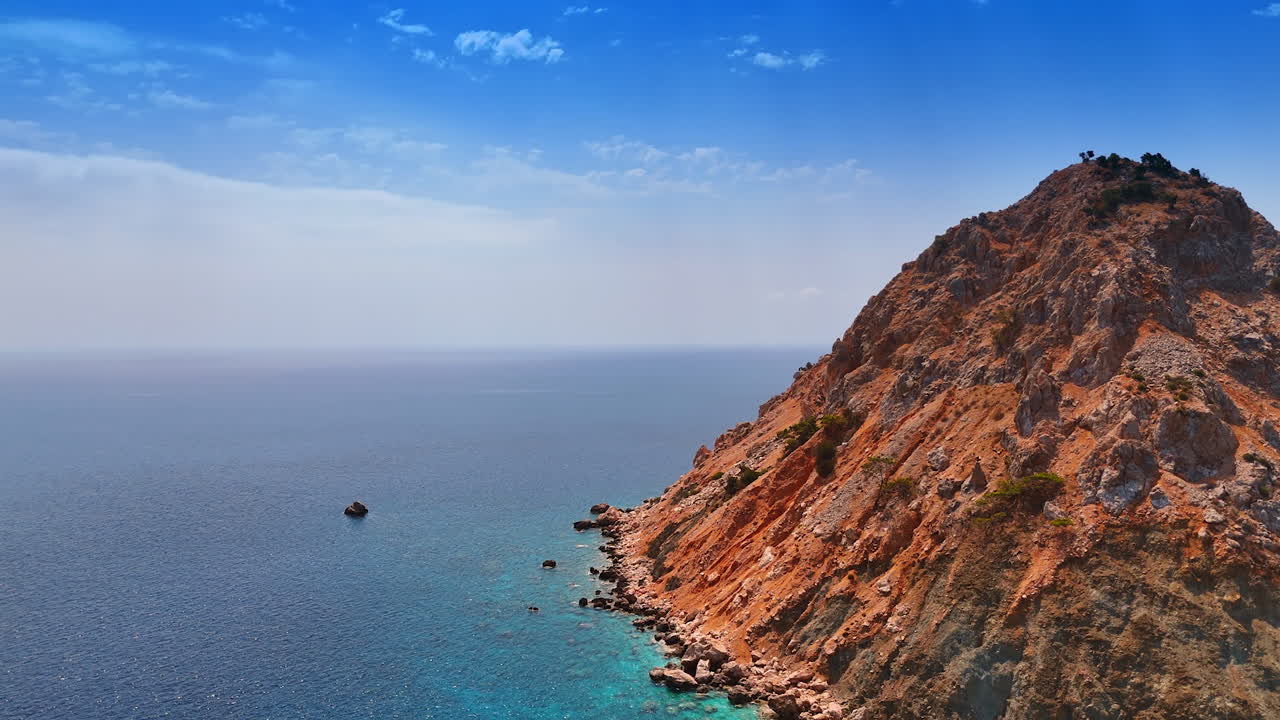 Coastal view with cliffs and clear water. Cliffs rise sharply from the turquoise sea under a clear blue sky