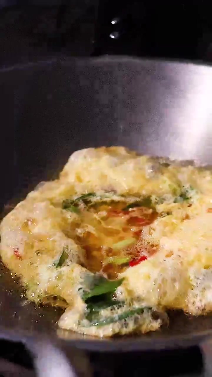 熱い中華鍋で唐辛子とネギ入りのオムレツを焼く