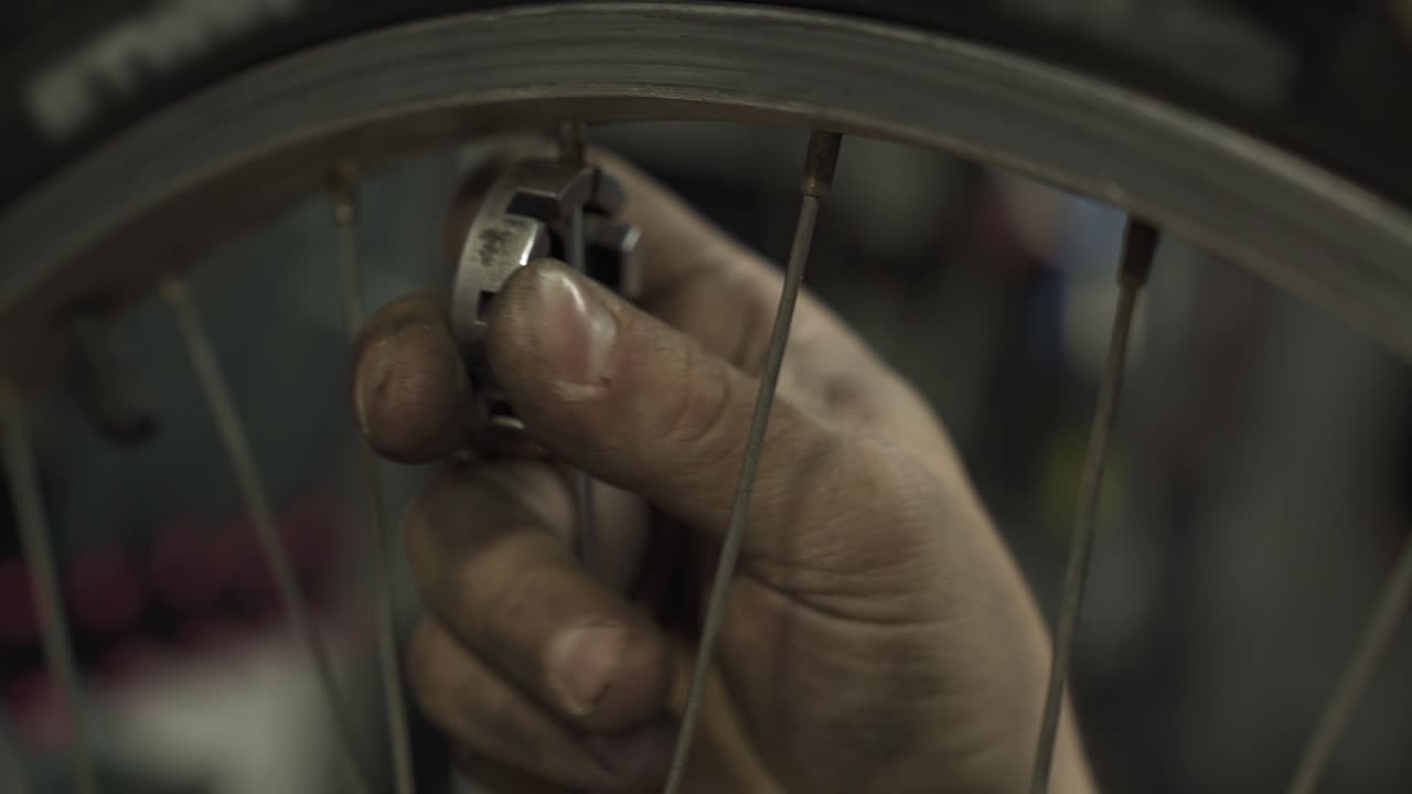 un mecánico de bicicletas apretando los pezones de las bicicletas