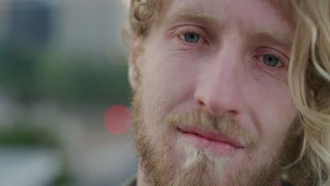 close-up-portrait-happy-young-man-smiling-enjoying-relaxed-urban-lifestyle-wind-blowing-hair-bearded-hipster-male-blue-eyes-slow-motion