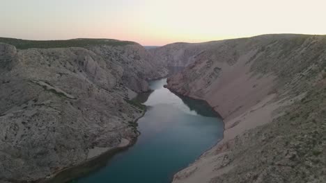 drone-flying-over-man-sitting-on-cliff-in-autumn-season-at-huge-sunset