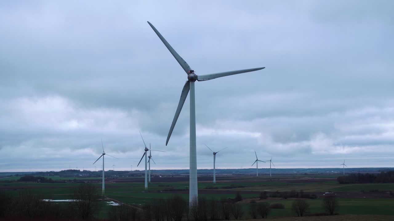 Close up view of renewable green energy technology windmill rotate creating power in rainy clouds sky background