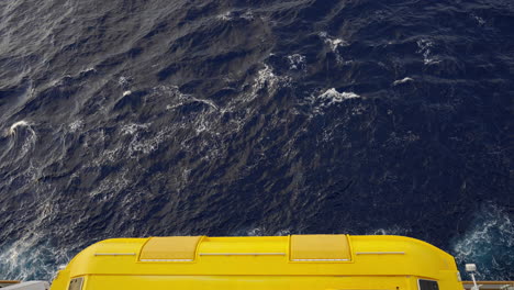 Yellow-lifeboat-on-the-side-of-a-cruise-ship-above-the-ocean