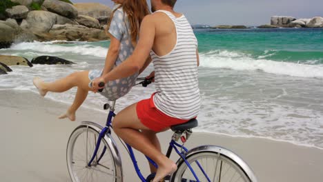 side view of caucasian couple riding a bicycle on the beach 4k