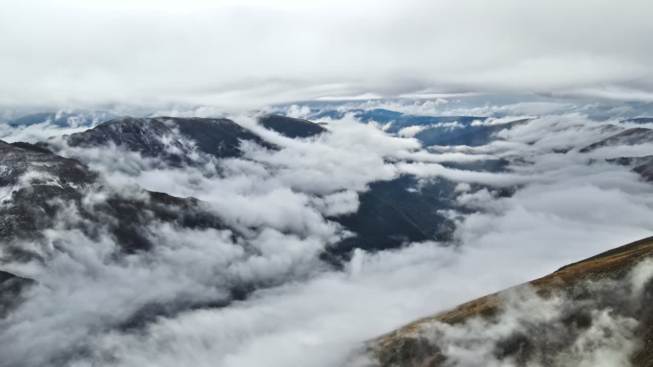 Aerial drone view of nature in Romania. Transfagarasan route in Carpathian mountains, snow on mountains rocky slopes, valley, clouds