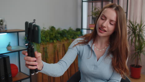 Young-business-woman-blogger-using-smartphone-shooting-video-call-for-social-media-at-home-office