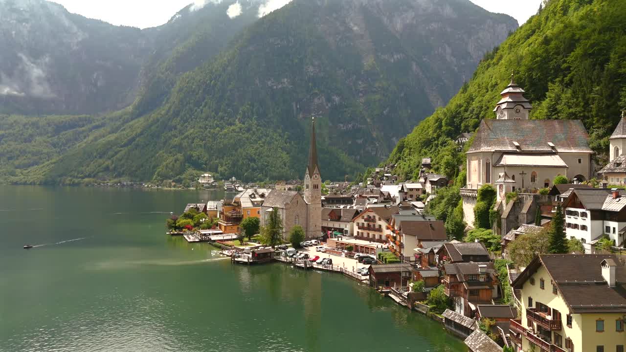 Aerial view of Hallstatt, Austria, captured by drone, showcasing its picturesque lakeside homes, majestic mountains, and the unique charm of this enchanting alpine village.
