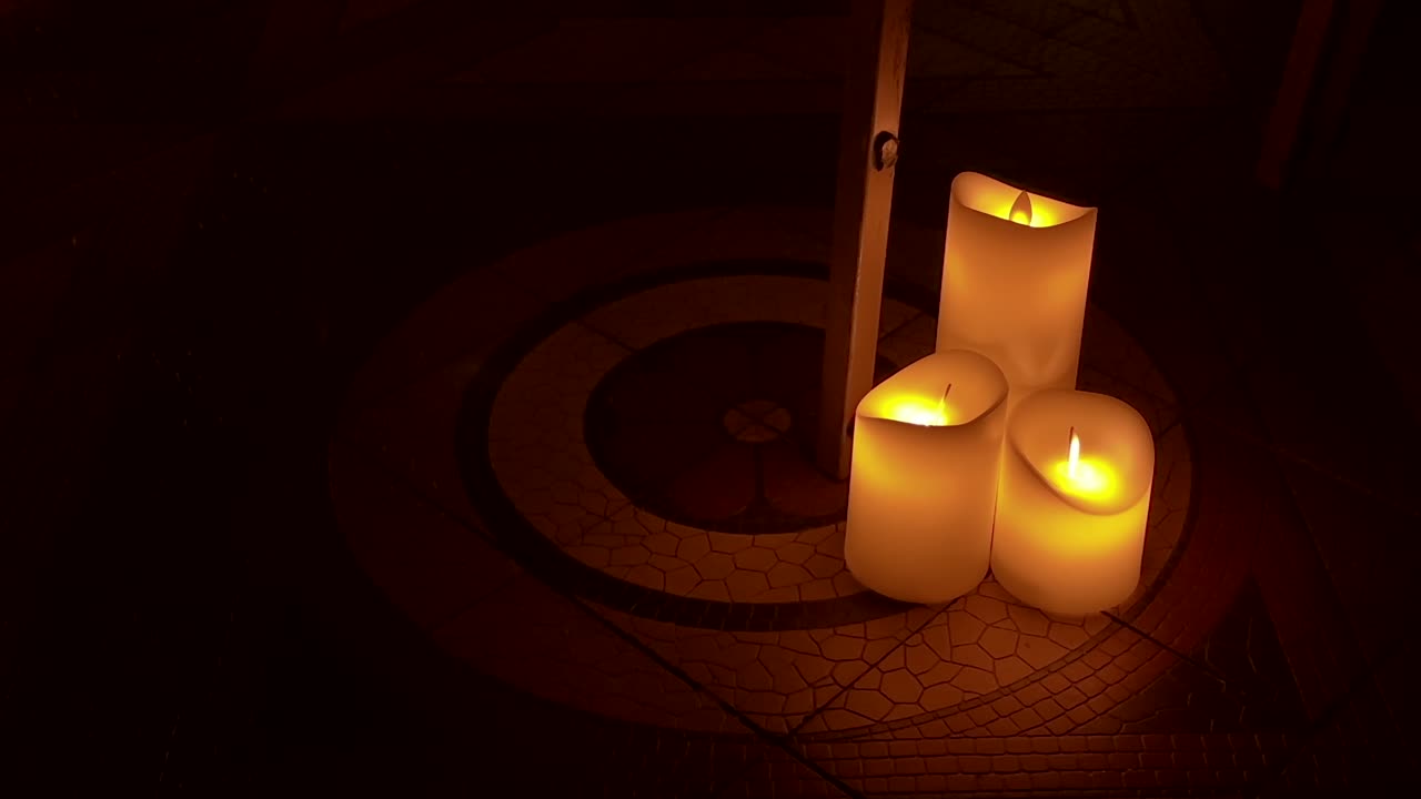 three soft candles lit on patterned floor in moody low light atmosphere