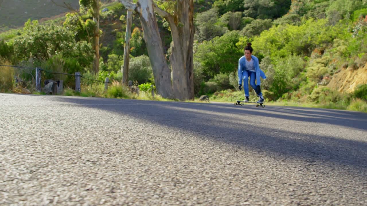 시골 도로 4k에서 스케이트보드 트릭을 하는 멋진 젊은 백인 남자의 앞면