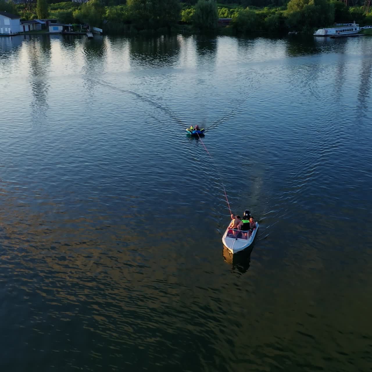 White boat on the river at sunset. People sailing in boats among beautiful landscape in the evening. Rest in summer. Aerial view.