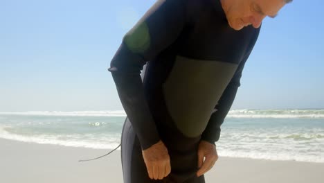 Side-view-of-active-senior-Caucasian-male-surfer-wearing-wet-suit-on-the-beach-4k