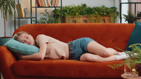 Tired lazy woman enjoy relaxing on home sofa resting napping after hard working day, closed her eyes