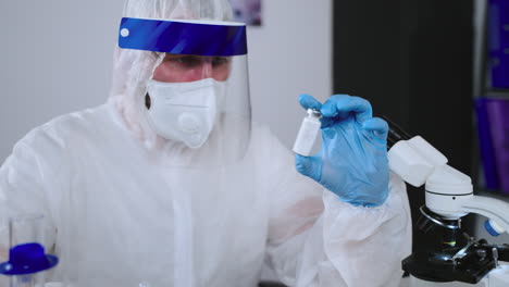 scientist in protective gear examining sample under microscope