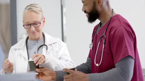 diverse male and female doctors drinking coffee in hospital, slow motion