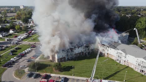 Water-being-poured-over-burning-senior-living-apartments-in-Michigan,-aerial-drone-view