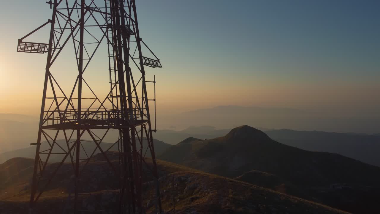 panorámica aérea de la silueta de una torre de telecomunicaciones en un pico de la montaña al amanecer