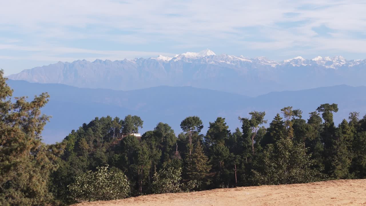 A breathtaking view of snow-capped Himalayan peaks towering above green foothills. The scene highlights dramatic elevation, fresh air, and the harmony between alpine and subtropical landscapes