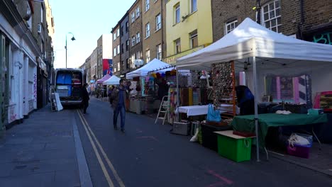 man walks past stands setting up at brick lane street market in london early morning