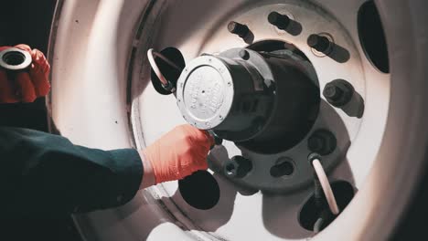 handheld-close-up-mechanic-with-orange-gloves-ties-lug-nuts-bolts-on-a-trailer