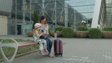 mother and daughter near airport. woman hold passports and tickets in hand. child and mom vacation