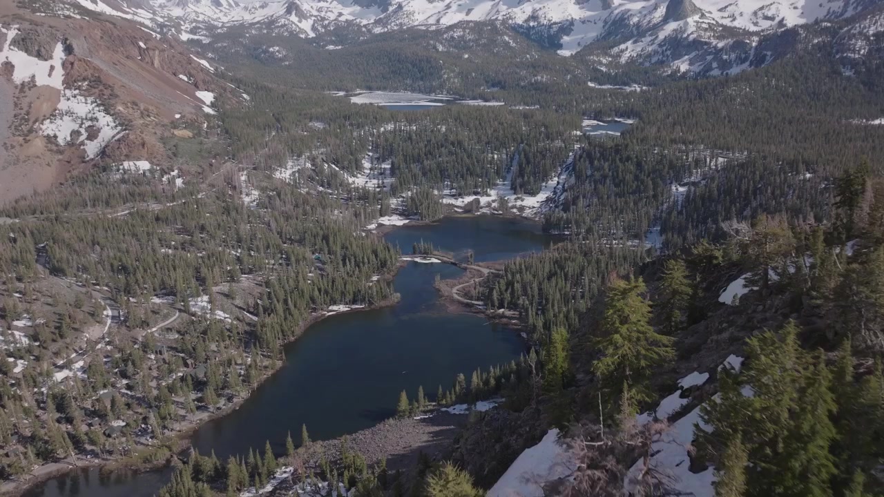 Ampia vista aerea sulla natura selvaggia d'alta quota che circonda i Twin Lakes a Mammoth Lakes, California, evidenziando i dolci crinali alpini, le distese sempreverdi e le cime frastagliate distanti.