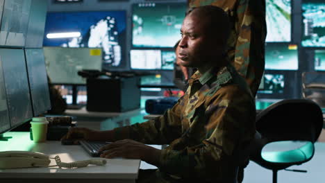 oficiales militares mirando las pantallas de los equipos de seguimiento para obtener información