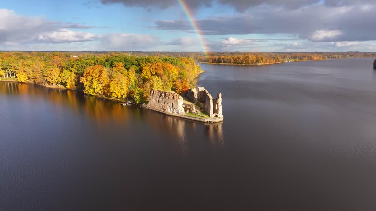 Koknese Castle ruins in Latvia with a double rainbow in the background on a beautiful autumn day