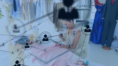 animación de una red de iconos de perfiles sobre una diseñadora de moda asiática usando una tableta en un estudio