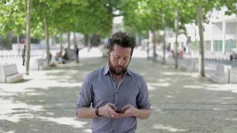 man walking on street and using smartphone