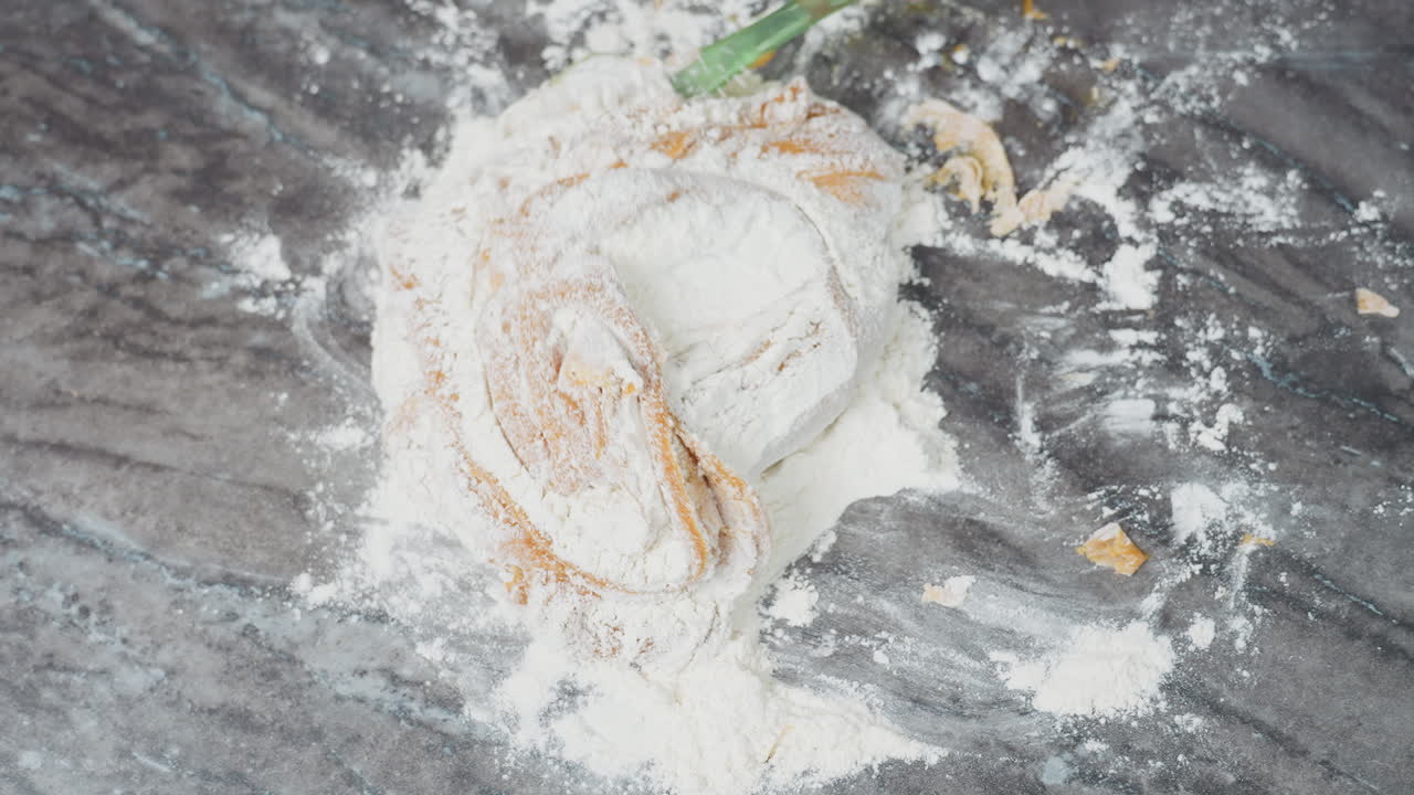 가루로 된 타일 테이블에서 반죽이 여있는 위에서 아래로 보이는 모습, 손으로 압축하고 접는 동안 표면에 어져있는 밀가루가 기 위해 준비되는 부드러운 반죽