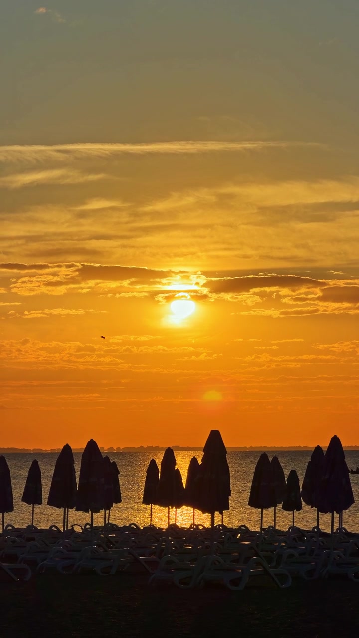 Solnedgang over havet med parasoller på stranden i kveldstimene