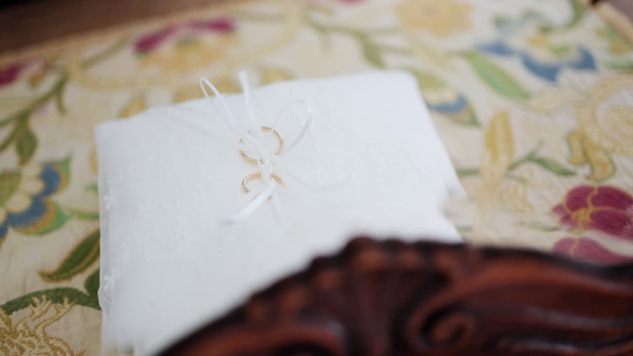 Soft white pillow with wedding rings tied with a ribbon, delicate and romantic