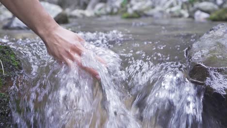 mano jugando con el agua del arroyo. cámara lenta.