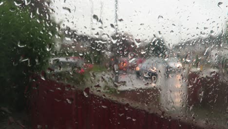 rain falling on window with blurred background of standing traffic outside on street