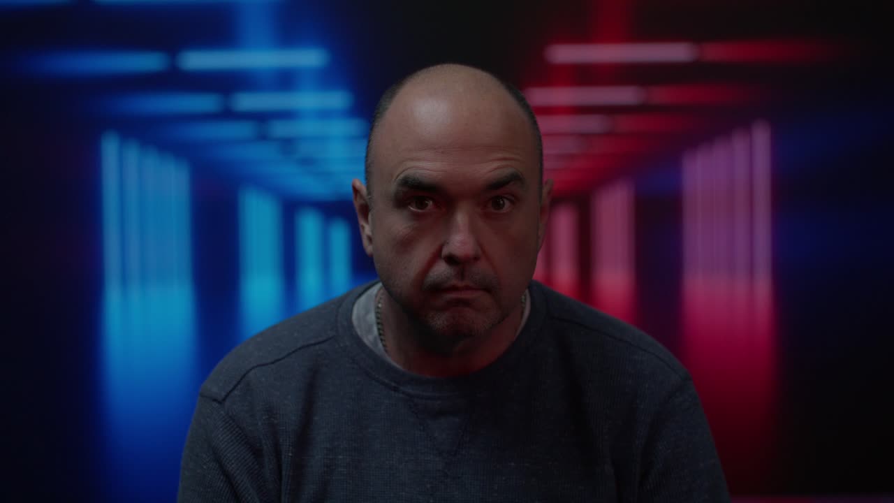 Middle aged white male looking up to camera with a stare with a moving colorful background